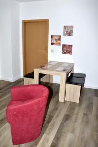 een houten tafel en een rode stoel in een kamer bij Ferienwohnung am Wasserturm in Zwenkau