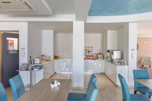 a kitchen and dining room with blue chairs and a table at Bellini Hotel in Ayia Napa