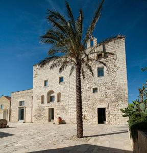 a palm tree in front of a stone building at Masseria Francescani in Torre Chianca