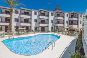 un apartamento con piscina frente a un edificio en Alsol Las Orquídeas, en Playa del Inglés