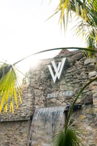 un cartello sul lato di un muro di pietra con un segno V di Jardines Villaverde a Villaverde Pontones