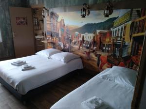 two beds in a room with a painting on the wall at Hotel Angelys in Ploërmel