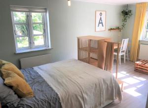 a bedroom with a bed and a table and windows at Askes Oase Guest Apartment in Fjællebroen