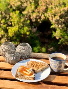 un piatto di pane e una tazza di caffè sul tavolo di Askes Oase Guest Apartment a Fjællebroen