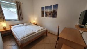 a bedroom with a bed and a desk and a television at B&B La Perla in Punat