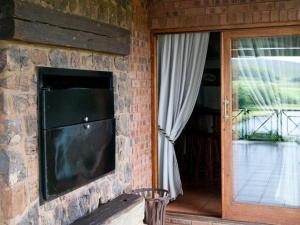 a stone wall with a tv and a window at Glen Aden in Dullstroom