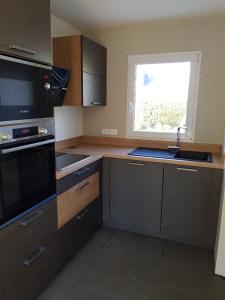 a kitchen with a sink and a stove and a window at Gîte mon plaisir in Carnac