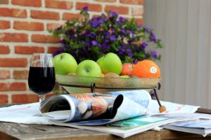 イーペルにあるB&B Laurusの- ワイン1杯とテーブルの上のフルーツバスケット