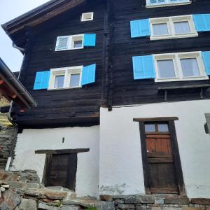 une maison en bois avec deux portes et fenêtres dans l'établissement Santorini by Quokka 360 - Blue curtains in the Alps, à Anzonico