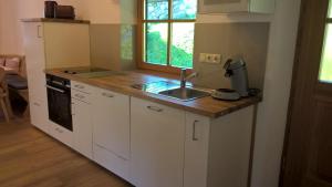 een keuken met witte kasten, een wastafel en een raam bij Haus Schönsicht in Berchtesgaden