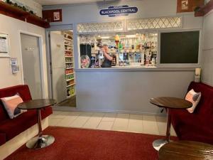 a restaurant with two tables and a bar with a woman at Bamford House Hotel in Blackpool
