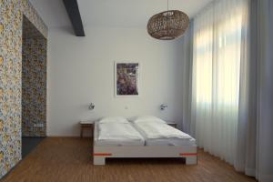 - une chambre blanche avec un lit et une fenêtre dans l'établissement Baumann & Müller, à Walsheim