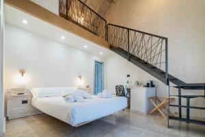 a bedroom with a large white bed and a staircase at Domo Pro Vois in Orosei