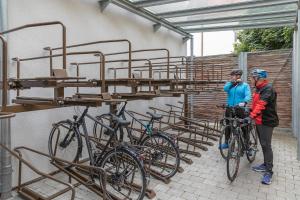 WassertrüdingenにあるRadlhotel Wassertrüdingenの二人の男が自転車の横に立って自転車棚に乗っている