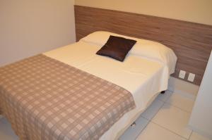 a bed with a brown pillow on top of it at Apartamento Costa Azul in Recife