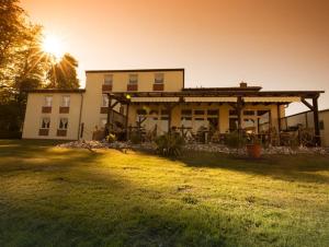 a house with the sun setting behind it at Hotel und Appartements Jägerhof Rügen in Lancken-Granitz