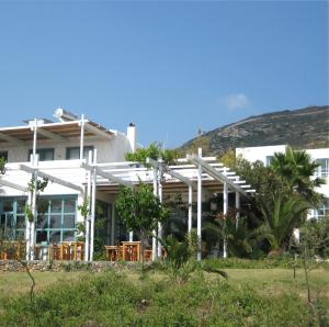 a white house with tables and chairs in front of it at Hotel Plakures in Falasarna
