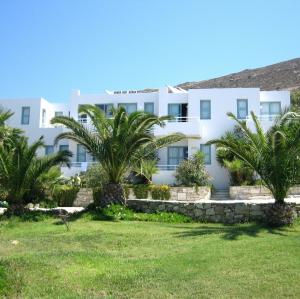 a large white building with palm trees in the foreground at Hotel Plakures in Falasarna