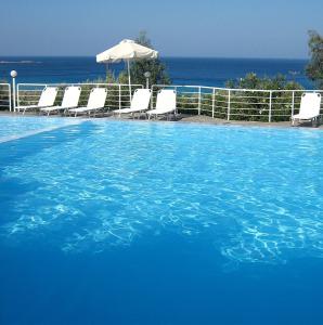 a large blue swimming pool with chairs and an umbrella at Hotel Plakures in Falasarna