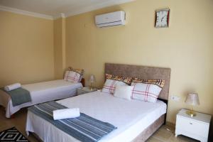 ein Schlafzimmer mit 2 Betten und einer Uhr an der Wand in der Unterkunft Kaş Güzey apart 3+1 Doğa ve deniz manzaralı in Kaş