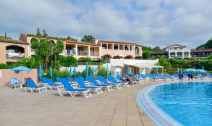 una piscina en el complejo con sillas y sombrillas en Résidence Pierre & Vacances Les Parcs de Grimaud, en Grimaud