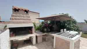 un patio con horno al aire libre y sombrilla en Vila Kula en Nin