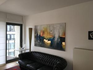 ein Wohnzimmer mit einem Sofa und einem Gemälde an der Wand in der Unterkunft Bel appartement Zeebruges in Zeebrugge