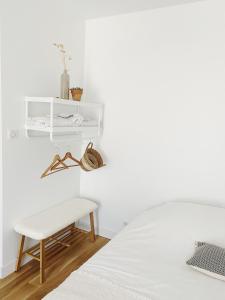 um quarto branco com uma cama e um banco em L'anne xe, studio indépendant em Valeuil