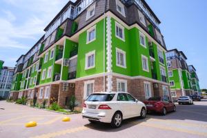 a white car parked in front of a green building at Art Lite One RED APARTMENTS in Adler