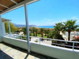 a balcony with a view of the ocean and palm trees at Hotel Plakures in Falasarna