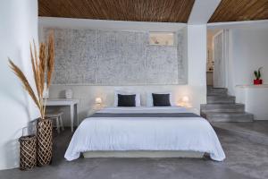 a bedroom with a large white bed and a staircase at Andronis Luxury Suites in Oia
