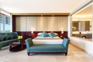 1 dormitorio con 1 cama, 1 silla y 1 sofá en Crowne Plaza Ahmedabad City Centre, an IHG Hotel en Ahmedabad