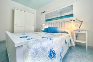 a white bedroom with a blue and white bed and a desk at Stella Marina in Santa Maria Navarrese
