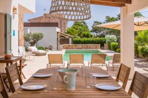 een houten tafel in een patio met een zwembad bij Casa Puro in Cala Llombards