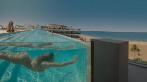 a woman swimming in a swimming pool next to the beach at RH Bayren Hotel & Spa 4* Sup in Gandía