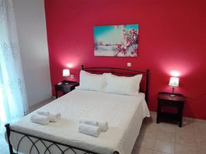 a red bedroom with a bed with towels on it at Katerina's home in Moraitika