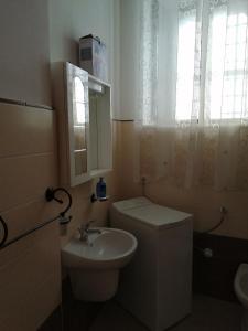 a bathroom with a toilet and a sink and a window at Casa Vacanze Il Quadrifoglio in Noto