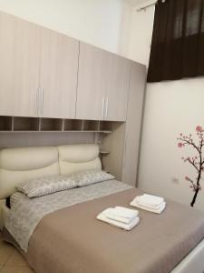 1 dormitorio con 1 cama con armarios blancos y toallas en Casa Vacanze Il Quadrifoglio, en Noto