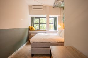a small bedroom with a bed and a window at Badhuis Hotel in Utrecht