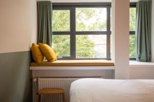 a bedroom with a window with yellow pillows at Badhuis Hotel in Utrecht