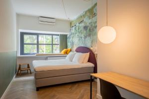 a small bedroom with a bed and a table at Badhuis Hotel in Utrecht