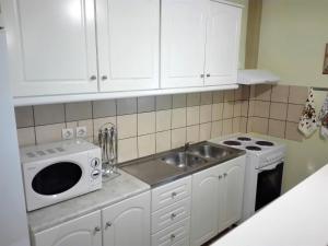 a kitchen with white cabinets and a sink and a microwave at Katerina's home in Moraitika