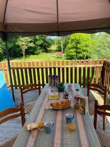 a picnic table under an umbrella with food on it at Gîte du Moulin in Gamarde-les-Bains