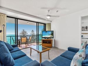 a living room with a blue couch and a tv at Peninsular Beachfront Resort in Mooloolaba