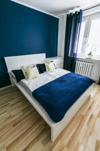 a bedroom with a bed with a blue wall at Apartament w Centrum III in Ustka