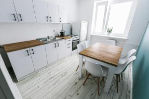 kuchnia z drewnianym stołem i białymi szafkami w obiekcie Apartament w Centrum III w Ustce