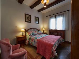 a bedroom with a bed and a chair and a window at Finca Engracia in Cudillero