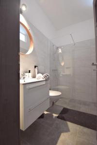 uma casa de banho branca com um lavatório e um chuveiro em Apartmány Ve stodole em Roudnice nad Labem