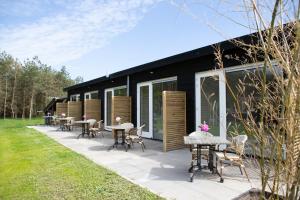 a patio with tables and chairs in front of a building at Natuur lodge in Blesdijke