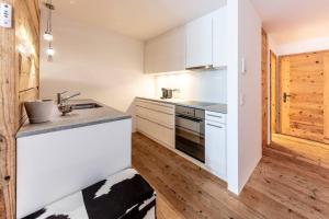 uma cozinha com armários brancos e piso em madeira em Residence Au Reduit Sankt Moritz em St. Moritz